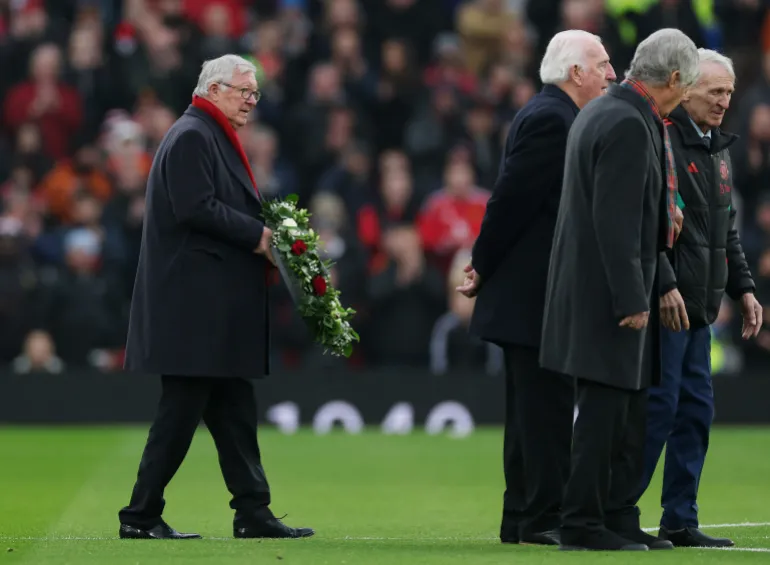 Former Manchester United manager Alex Ferguson holds a wreath in memory of former Manchester United player Denis Law